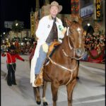 Man in a white jacket riding a chestnut brown horse